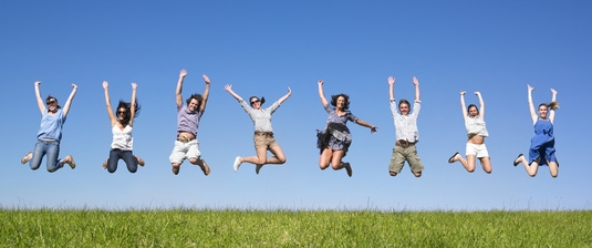 Group of friends Jumping in meadow under blue sky